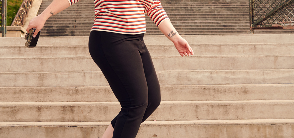 Eine Frau in einer engen schwarzen Hose geht eine Treppe herunter