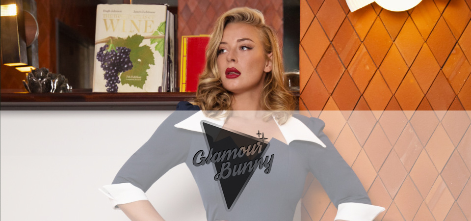 Eine Frau in einem blauen 50er Jahre Kleid mit weißem Kragen, Logo der Marke Glamour Bunny